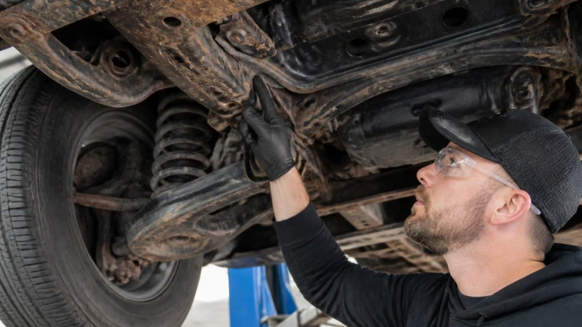 Diagram showing critical vehicle areas undercoating points on a rusty car frame and suspension system.